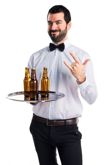 Garçon avec des bouteilles de bière sur le plateau faisant un geste de corne