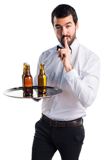 Garçon avec des bouteilles de bière sur le plateau faisant un geste de silence