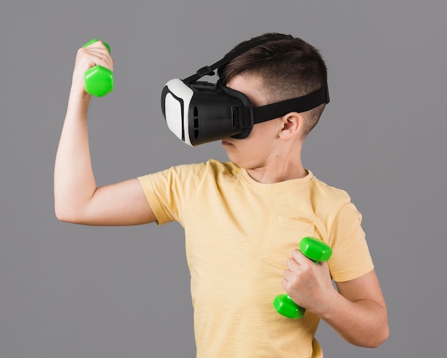 Garçon avec casque de réalité virtuelle tenant des poids