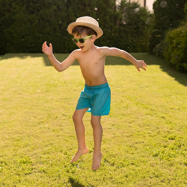 Photo gratuite garçon avec chapeau et lunettes de soleil sautant