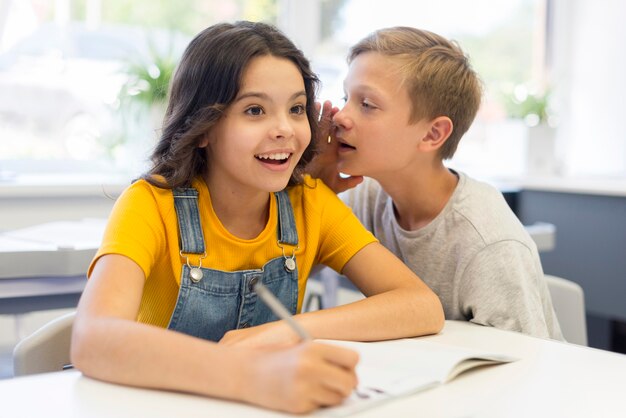 Garçon chuchoter à une fille en classe