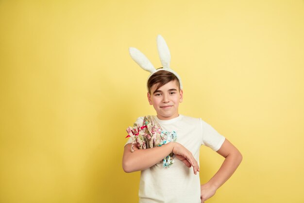 Garçon comme un lapin de Pâques sur le mur jaune du studio