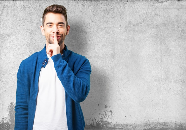 Garçon dans une veste bleue en souriant et en demandant le silence