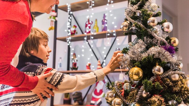 Garçon décorer un arbre de Noël