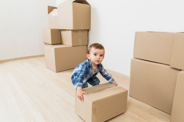 Garçon enfant jouant avec une boîte en carton en mouvement à la nouvelle maison