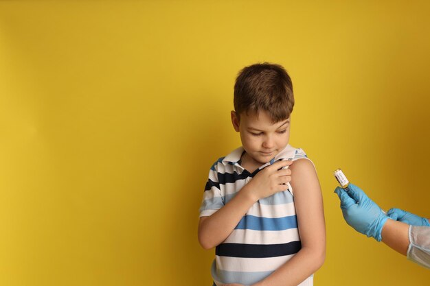 Le garçon est vacciné dans le contexte d'une main dans des gants et avec une seringue espace réservé au texte