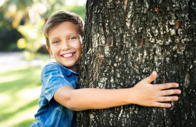 Garçon étreignant un grand arbre dans le parc