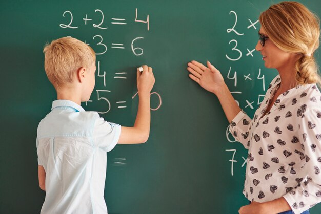 Garçon étudiant à la craie à côté du tableau