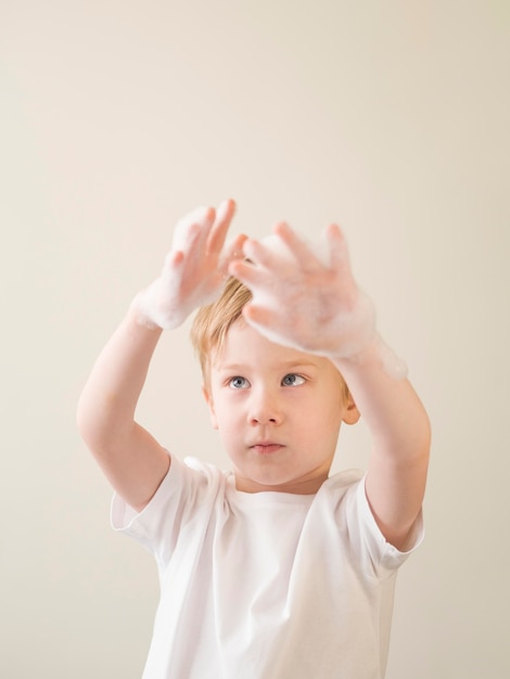 Garçon de faible angle avec mousse de bain sur les mains