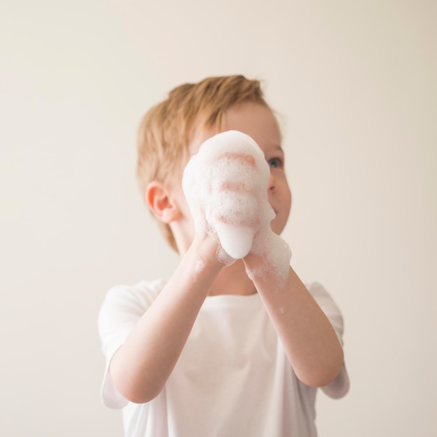 Garçon à faible angle avec de la mousse sur les mains