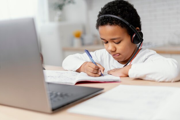 Garçon à faire ses devoirs avec l'utilisation d'un ordinateur portable