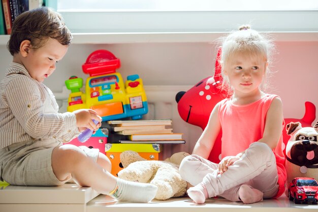 Garçon et fille assis à la fenêtre posant