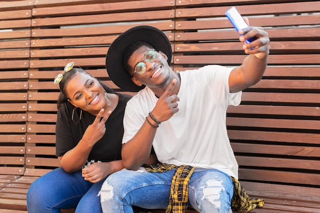 Garçon et fille assise sur un banc tout en prenant un selfie