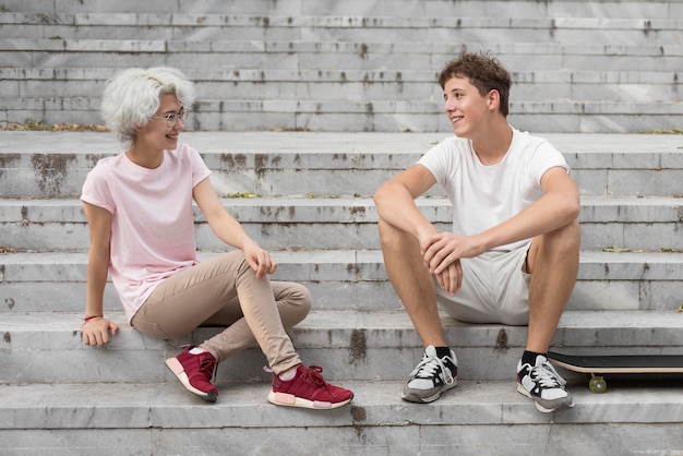 Photo gratuite garçon et fille parlant assis sur les escaliers