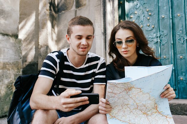 Garçon et fille s&#39;asseoir sur les marches de la cathédrale avec la carte touristique