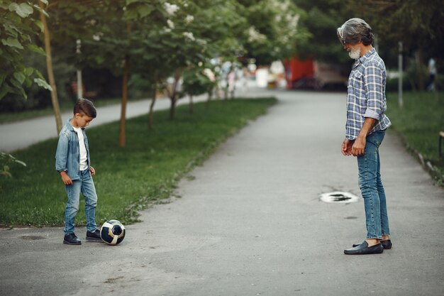 Garçon et grand-père marchent dans le parc. Vieil homme jouant avec son petit-fils. Famille jouant avec un ballon.