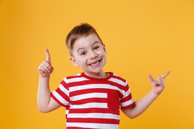 Garçon Heureux Souriant Pointant Les Doigts Vers Le Haut Au Fond