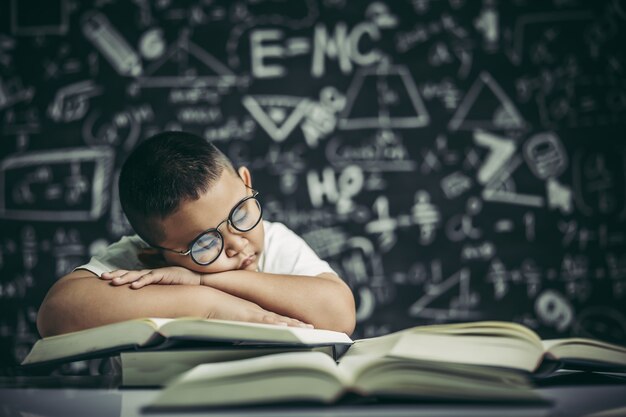 Un garçon avec des lunettes étudie et somnolent.