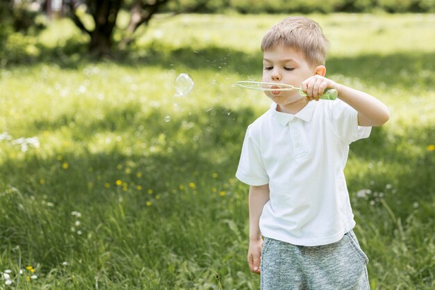 Garçon mignon, soufflant des bulles dans le parc