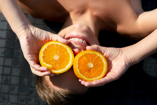 Photo gratuite garçon à la piscine avec orange