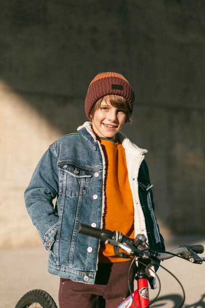 Garçon posant avec son vélo à l'extérieur de la ville