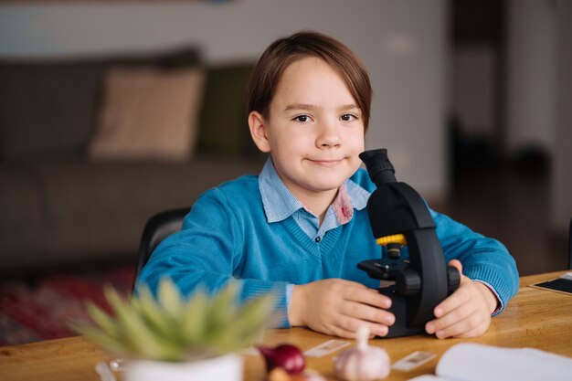 Garçon de première année étudiant à la maison à l'aide d'un microscope