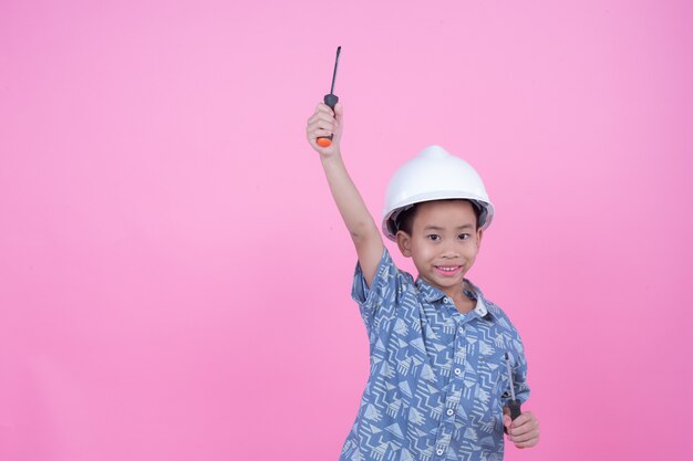 Un garçon qui a fait un geste de ses mains portant un casque sur un fond rose.