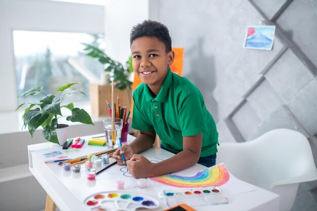 Garçon regardant la caméra couvrant le dessin à la main