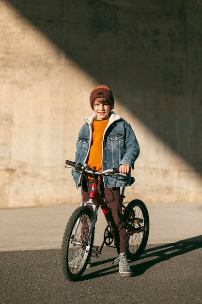 Garçon avec son vélo à l'extérieur de la ville