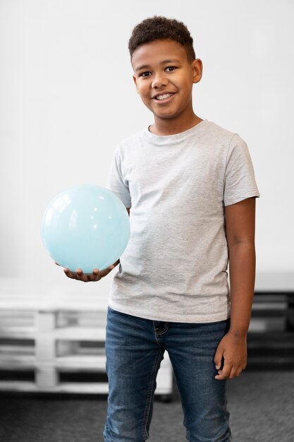 Garçon souriant de coup moyen tenant le ballon