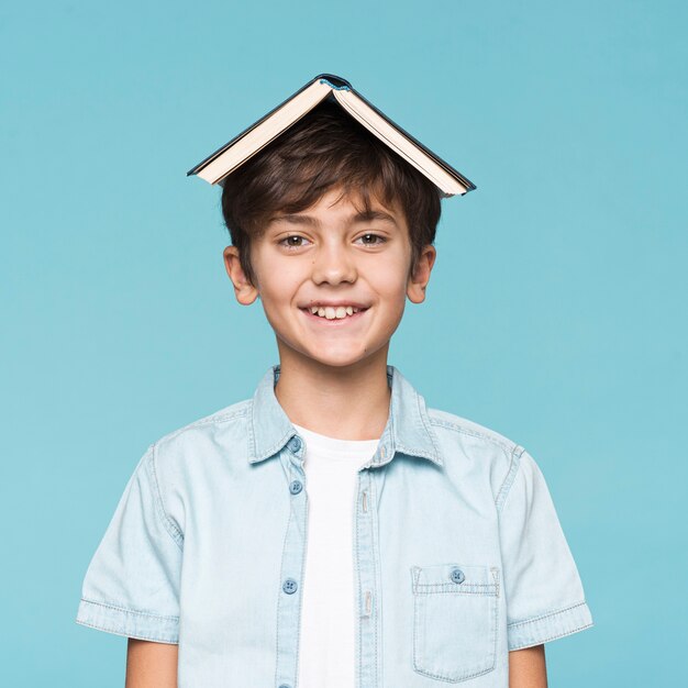 Garçon souriant avec livre sur la tête