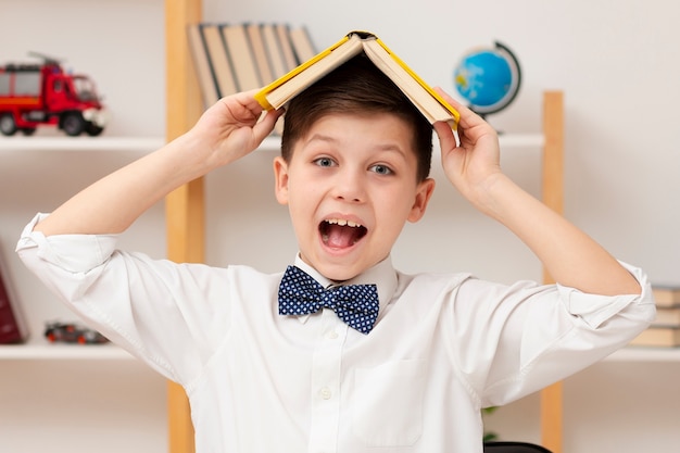 Garçon souriant avec livre sur la tête