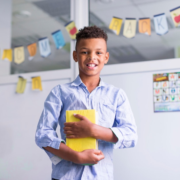 Photo gratuite garçon souriant tenant un livre en classe