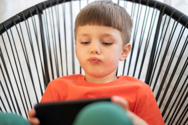 Garçon avec tablette jouant sur chaise