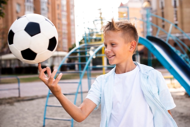 Photo gratuite garçon tenant un ballon de foot sur un doigt