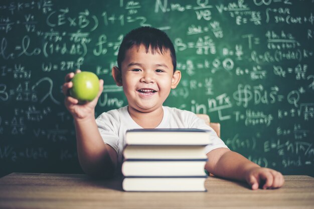 garçon tenant une pomme dans la salle de classe