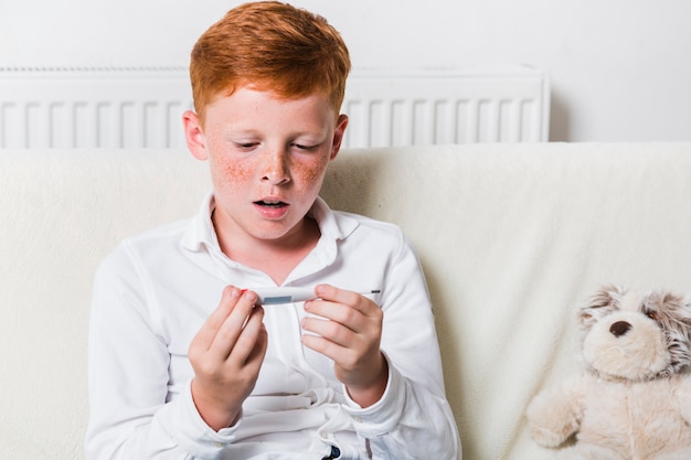 Garçon vue de face en regardant un thermomètre