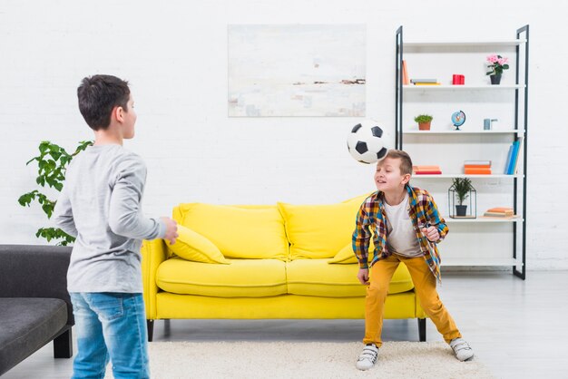 Garçons jouant au football dans le salon