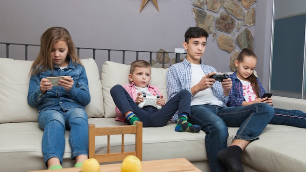 Garçons jouant à des jeux vidéo et filles utilisant des smartphones