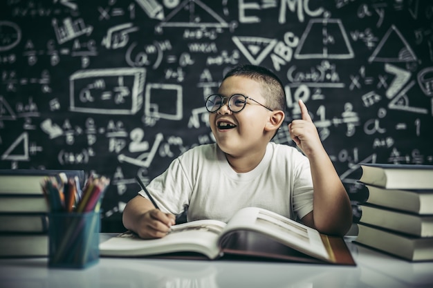 Les garçons avec des lunettes écrivent des livres et réfléchissent en classe