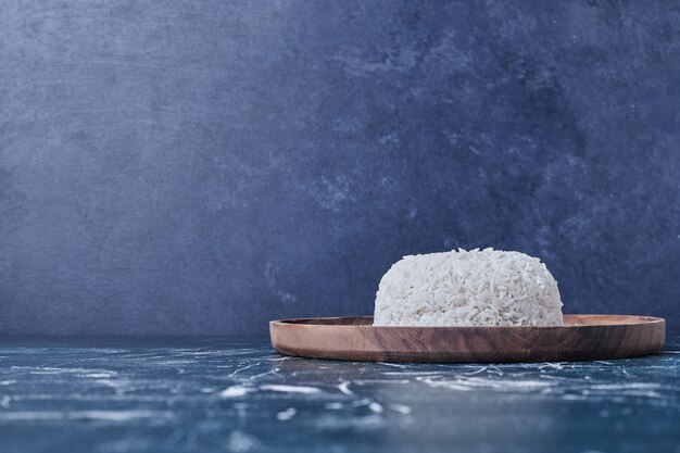 Garniture de riz dans une assiette en bois.