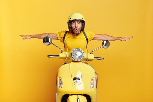 Photo gratuite un gars choqué avec un casque conduisant un scooter jaune