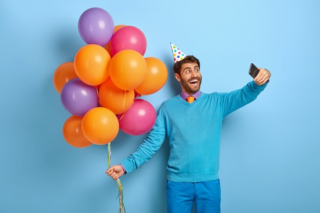 Un gars européen positif s'amuse à une fête d'entreprise, fait un portrait de selfie sur un téléphone portable