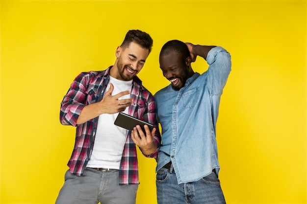 Les gars européens et afro-américains regardent la tablette et rient