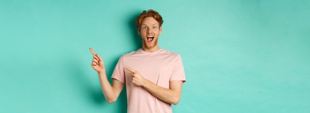 Photo gratuite un gars excité en t-shirt rose montrant une publicité sur fond de menthe à la surprise de l'appareil photo et du poi