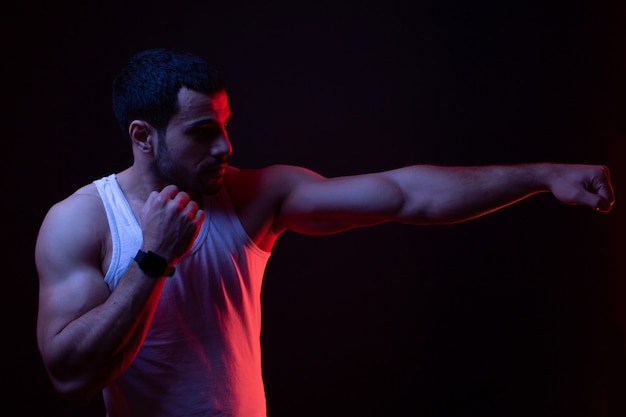 Un gars en position de boxe dans une pièce sombre