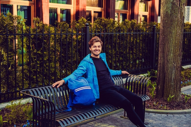 Un gars souriant dans un vêtement de sport assis sur un banc.