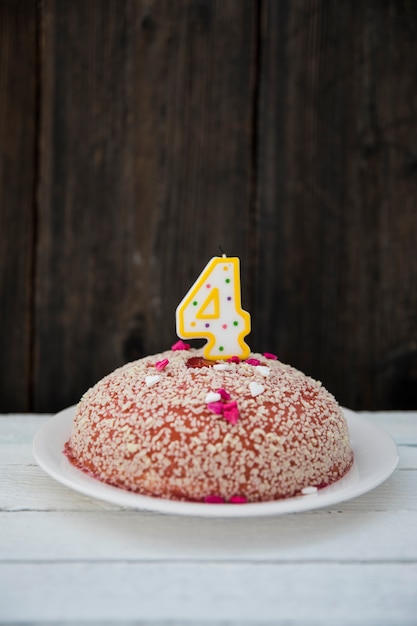 Gâteau d&#39;anniversaire avec quatre bougies numérotées sur une table en bois