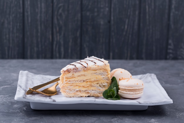 Gâteau sur une assiette avec des couverts et des macarons