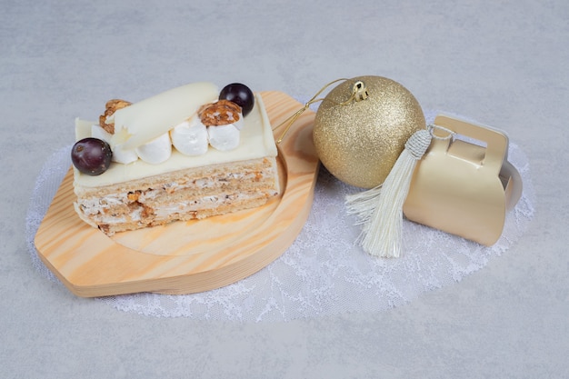 Gâteau au chocolat blanc sur plaque en bois avec cadeau de Noël et boule. Photo de haute qualité